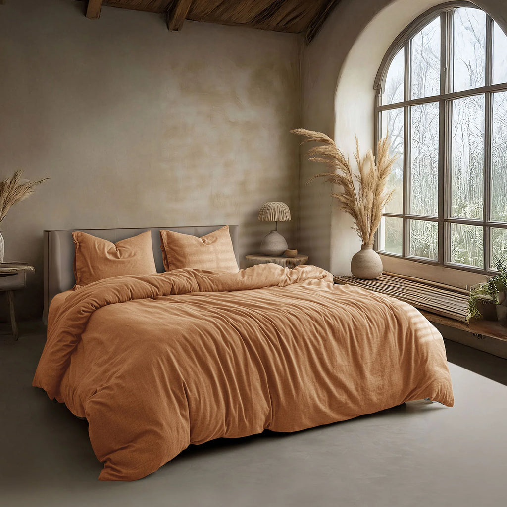 Cozy bedroom with a bed covered in brown bedding, large window, and decorative elements.