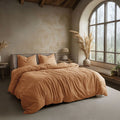 Cozy bedroom with a bed covered in brown bedding, large window, and decorative elements.