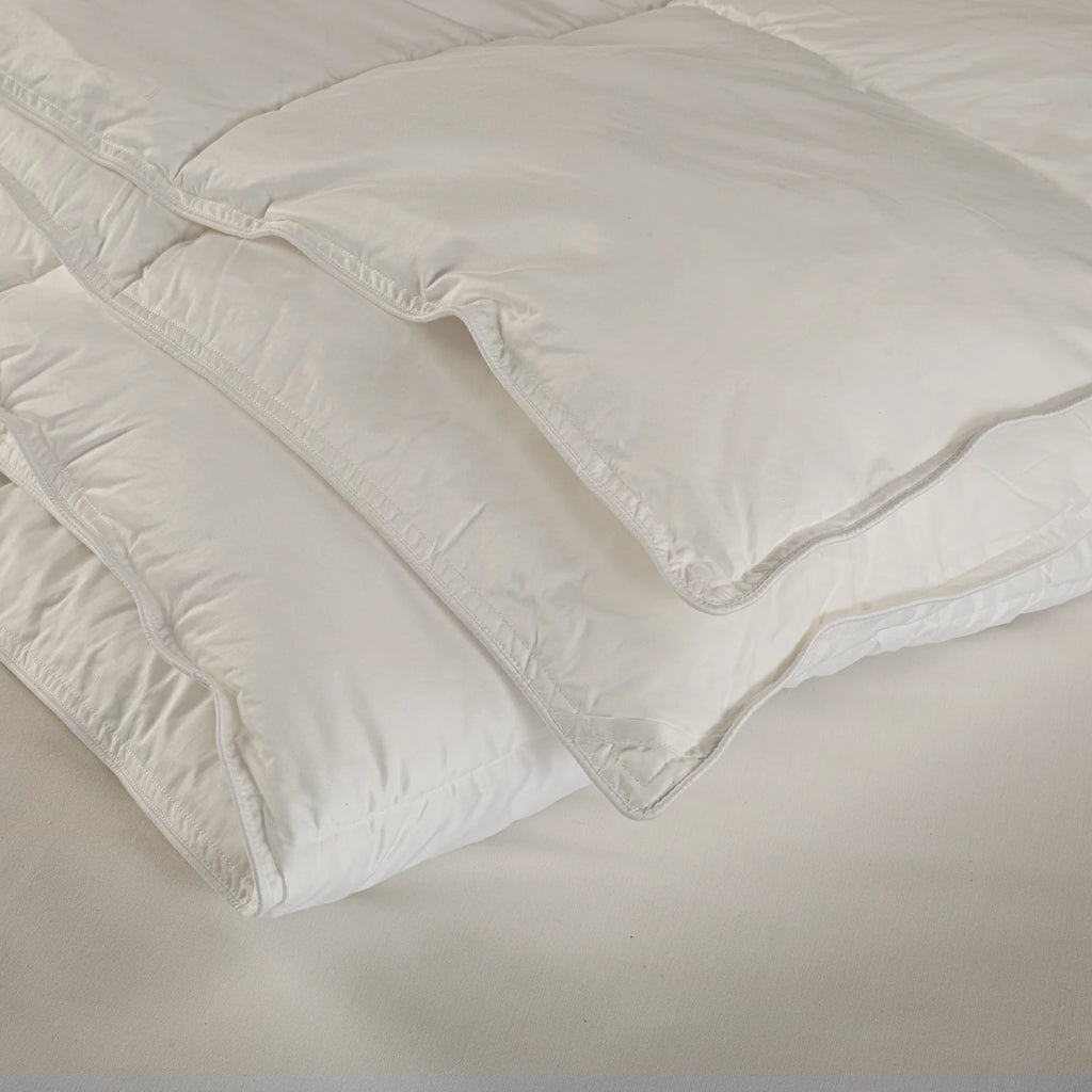 White comforter on a bed with a neutral background