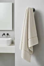 Beige towel hanging on a black towel rack in a bathroom.