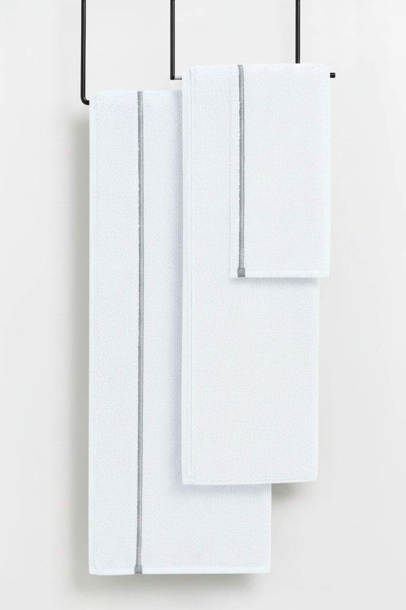 Set of white towels hanging on a rack against a white background
