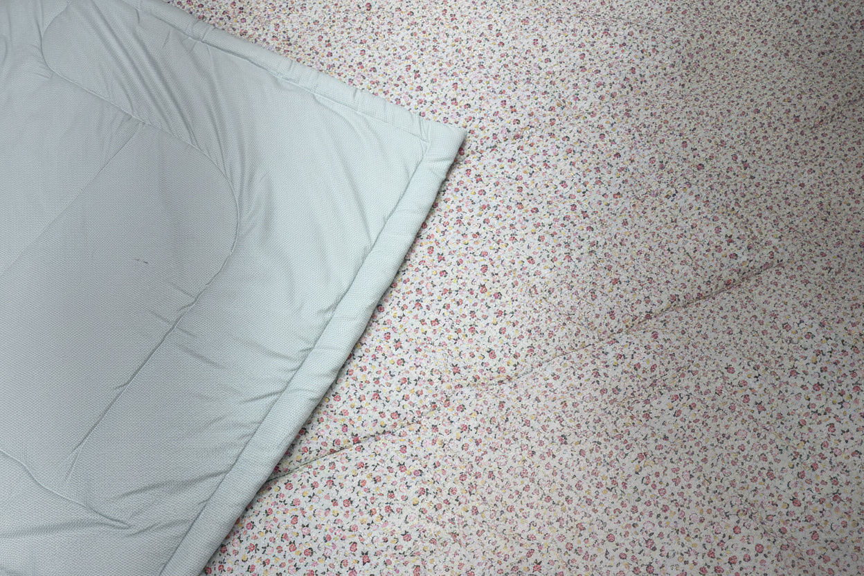 Floral Quilt with a light blue blanket partially covering it