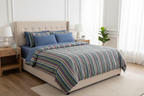 Bedroom with a bed featuring striped blue Quilt.