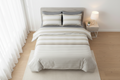 Striped bedspread set on a bed with pillows against a neutral background